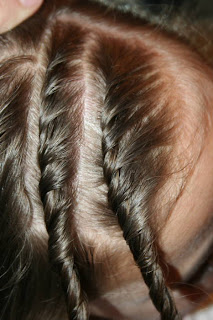 Close up of young girl's hair being styled into "Hair Twists into Messy Buns" hairstyle 