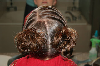 Back view of young girl's hair styled into "Triple Twists and Messy Buns"