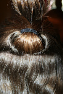 Back view of young girl's hair being styled into "Flip Braided Heart" hairstyle