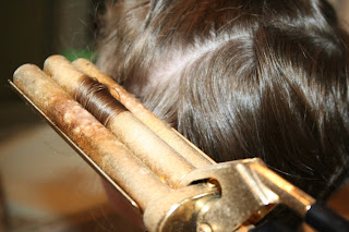 close up view of young girl's hair being styled into 3-barrel curl hairstyle on her a-line bob