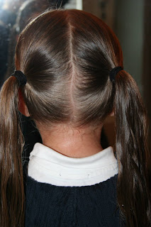 Back view of young girl's hair being styled into "Y" braid hairstyle