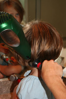 Side view of young girl's hair being styled with a blow dryer and round brush