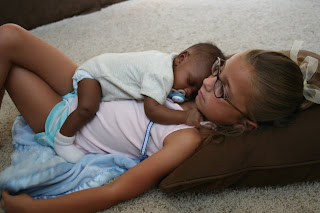 Young sister with her infant baby brother sleeping on her chest