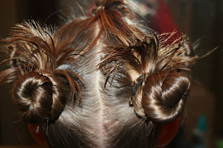 Close up view of young girl's hair being styled into "Holiday Twisty Buns" hairstyle