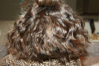 back view of young girl's hair being styled into 3-barrel curl hairstyle on her a-line bob