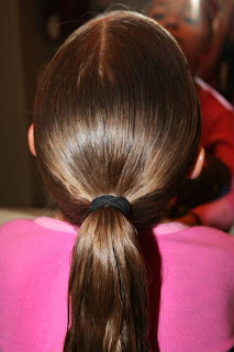 Back view of young girl's hair being styled into "Triple-Twist Ponytail' hairstyle