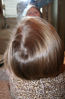 back view of young girl's hair being styled into 3-barrel curl hairstyle on her a-line bob