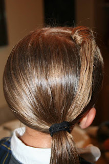 Back view of young girl's hair being styled into "Top-Knot with Banded" Ponytail