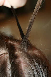 Close up of young girl's hair being styled into "Hair Twists into Messy Buns" hairstyle 