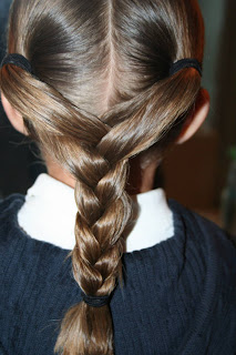 Close up view of young girl's hair being styled into "Y" braid hairstyle