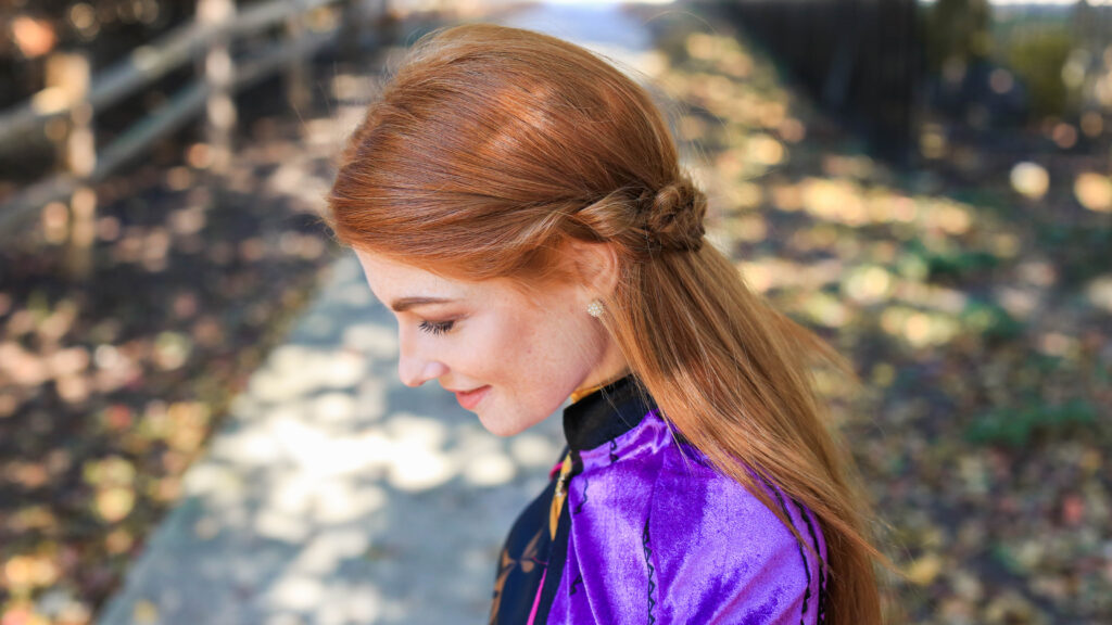 Profile view of long hair woman with Frozen inspired back braid hairstyle.