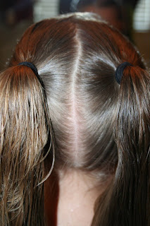 Back view of young girl's hair being styled into "Two-Leaf Clover" hairstyle