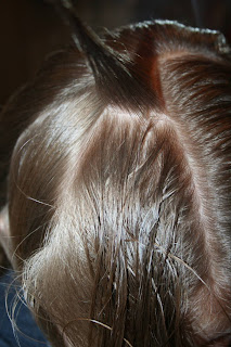 Close up view of a young girl's hair being styled into “French Designer Heart” hairstyle