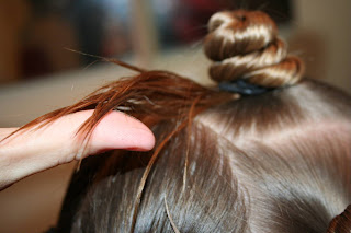 Close up view of young girl's hair being styled into "Holiday Twisty Buns" hairstyle