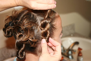 Back view of young girl's hair being styled into "4 Messy-Pigtail Twists" hairstyle