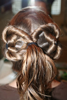 Back view of young girl's hair being styled into "Two-Leaf Clover" hairstyle