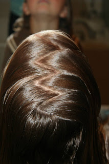 Young girl's hair being styled into "Pretzel-Twist Messy Bun"