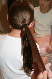 Back view of young girl's hair being styled into "Teen Hair Bun" hairstyle