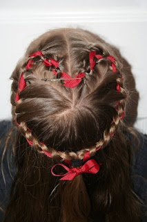 Top view of a young girl modeling “French Designer Heart” hairstyle with ribbon in her hair