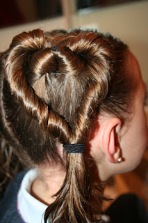 Side view of a young girl's hair being styled into “Two Hearts Twist” hairstyle