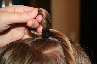 Close up view of young girl's hair being styled into "Top-Knot with Banded" Ponytail