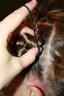 Side view of young girl's hair being styled into "4 Messy-Pigtail Twists" hairstyle