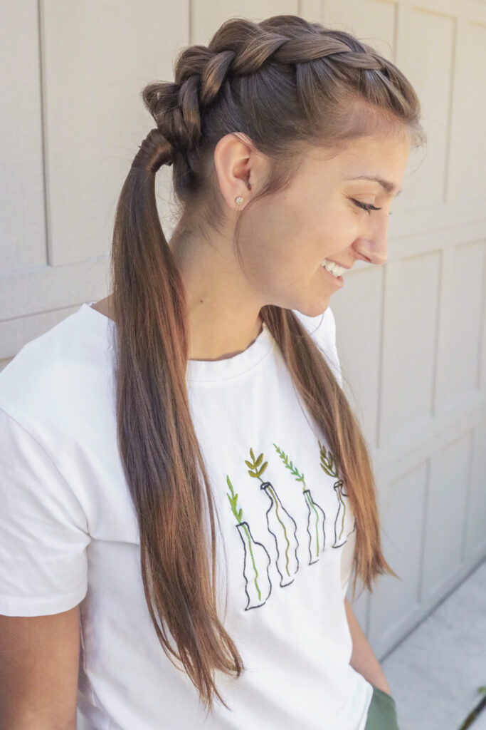 Profile shot of girl with long brown hair standing outside modeling the "Double Dutch Wrap" hairstyle