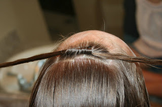 Close up view of young girl's hair being styled into "Knots into Side Ponytail" hairstyle