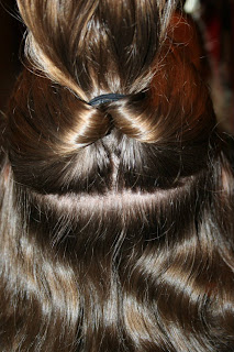 Back view of young girl's hair being styled into "Flip Braided Heart" hairstyle