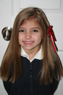 Portrait view of young girl modeling "teen heart" hairstyle 3 styled with a red ribbon