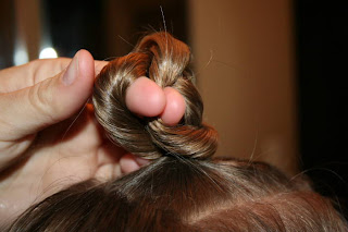 Close up view of young girl's hair being styled into "Top-Knot with Banded" Ponytail