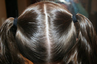 Back view of young girl's hair being styled into "Two-Leaf Clover" hairstyle