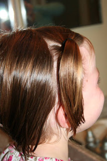 Side view of young girl's hair being styled into "twisty buns" hairstyle