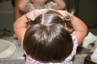 Top view of young girl's hair being styled into "twisty buns" hairstyle