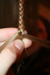 Close up view of young girl's hair being styled into "Teen Slide-Up Braid" hairstyle outside