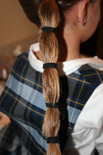 Back view of young girl's hair being styled into "Top-Knot with Banded" Ponytail