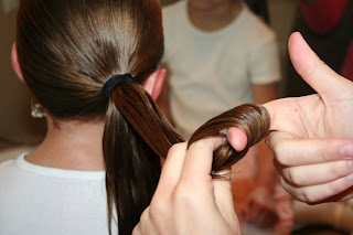 Back view of young girl's hair being styled into "Teen Hair Bun" hairstyle