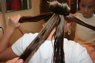 Back view of young girl's hair being styled into "Teen Hair Bun" hairstyle