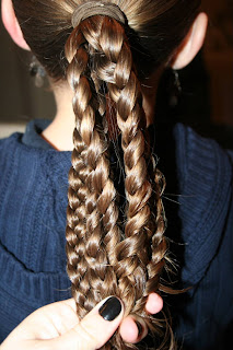 Back view of young girl's hair being styled into "bundled braids" hairstyle