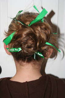 Back view of young girl modeling "Messy Bun" hairstyle styled with green ribbon hair accessory