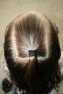 Top view of young girl's hair being styled into "The Bun-Hawk" hairstyle