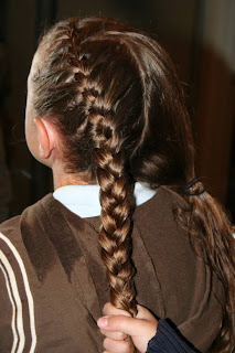 Back view of young girl's hair being styled into "Double-French Braids w/Messy Flips"