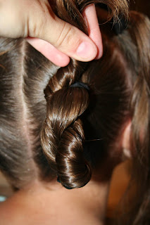 Back view of young girl's hair being styled into "4 Messy-Pigtail Twists" hairstyle