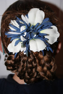 Back view of young girl modeling "bundled braids" hairstyle styled with floral hair accessories