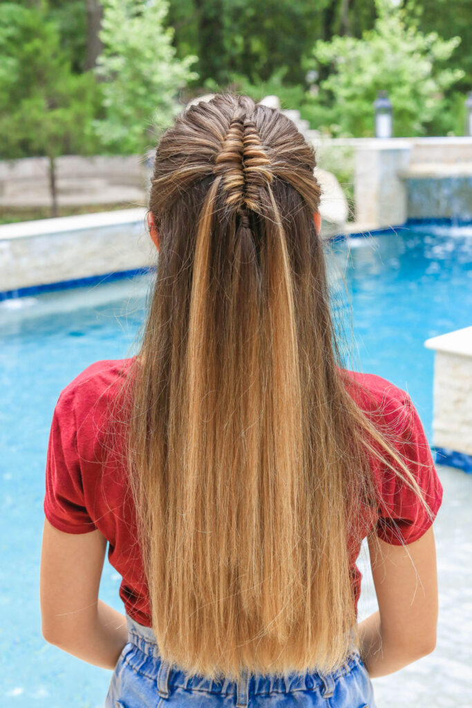 Back view of girl by the pool with long hair and showcasing long infinity braid