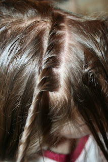 Close up of young girl's hair being styled into "Hair Twists into Messy Buns" hairstyle 