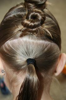 Back view of young girl's hair being styled into "The Bun-Hawk" hairstyle