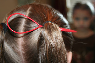 Back view of young girl's hair being styled into "Two-Leaf Clover" hairstyle