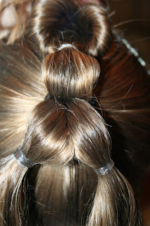 Back view of young girl's hair being styled into "Three-Leaf Clover Twists" hairstyle