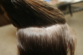 Back view of young girl's hair being styled into "The Bun-Hawk" hairstyle